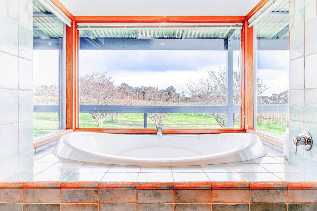 A gorgeous bath tub at the Wills Domain homestead features views over the vineyards, perfect for a leisurely soak with a glass or two of wine.