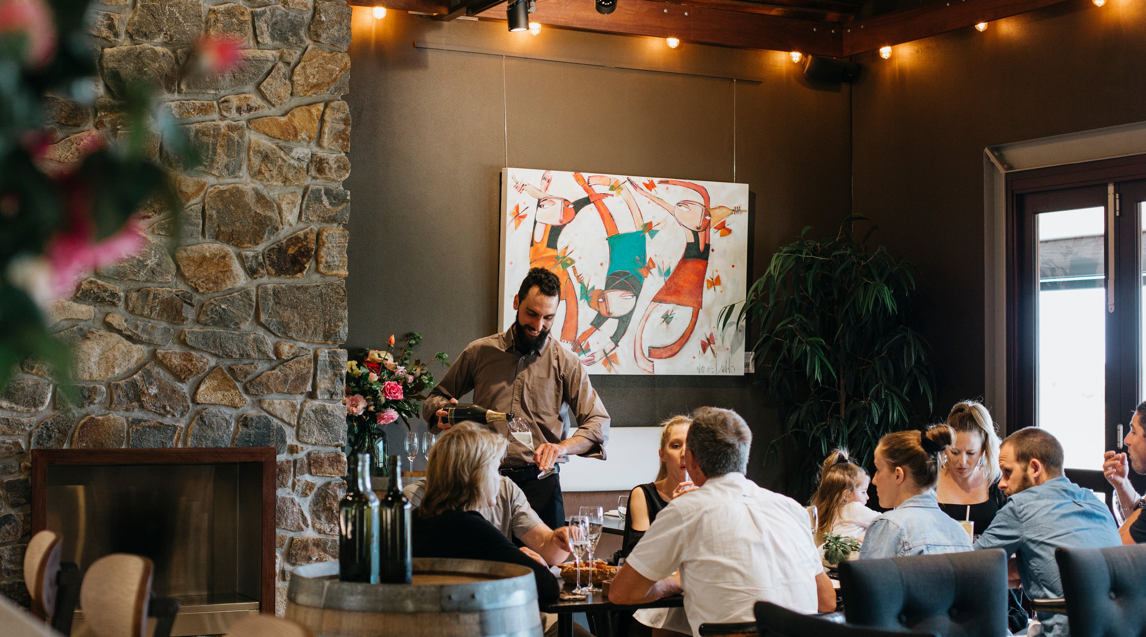 The Restaurant with guests dining and a staff member serving Wills Domain’s superb Cuvée d’ Élevage sparkling wine.