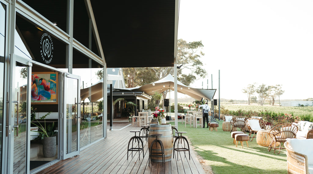 The Restaurant deck at Wills Domain overlooking the vineyards is a popular Margaret River wedding and events venue. The lawns and deck at Wills Domain set up for a function with lounge seating, floral arrangements, and a PA system create an ideal vineyard
