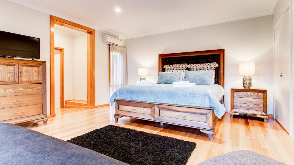 A bedroom at the Wills Domain homestead featuring rich wooden floors and a very comfortable bed - the perfect farmstay in Margaret River.